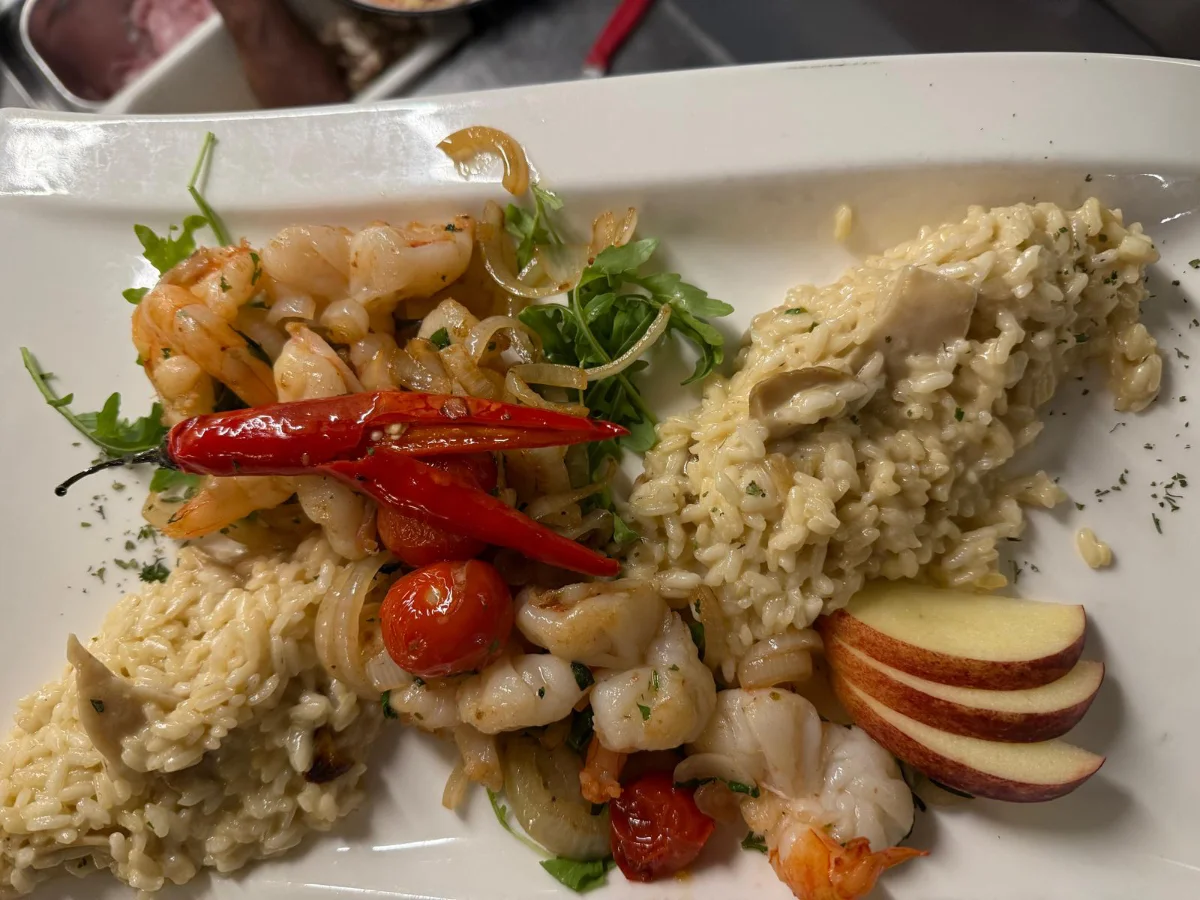 Ein Teller mit gebratenem Fisch, goldenen Kartoffeln und einer frischen Orangenscheibe.