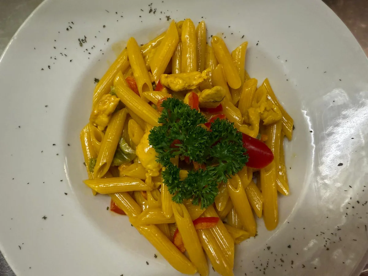 Ein Teller mit gebratenem Fisch, goldenen Kartoffeln und einer frischen Orangenscheibe.