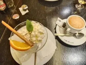Ein Tisch, auf dem ein Glas Kaffee und ein leckeres Dessert stehen.