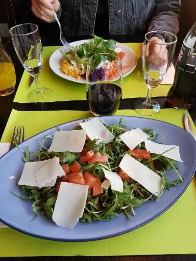 Ein Teller mit Essen auf einem Tisch, umgeben von Besteck und einem Glas Wasser.